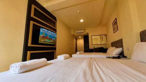 a hotel room with two beds and a flat screen tv at Bishop Hotel in George Town