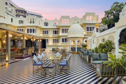 un patio al aire libre con sillas y mesas y un edificio en Swaroop Vilas - Lake Facing Boutique Hotel, en Udaipur