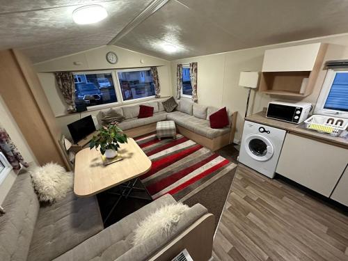 ein kleines Wohnzimmer mit einem Sofa und einem Tisch in der Unterkunft Two Bedroom Willerby Parkhome in Uddingston, Glasgow in Uddingston