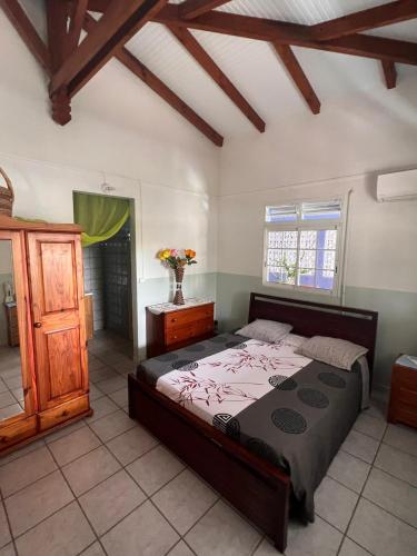 a bedroom with a large bed and a wooden cabinet at La Marie-Galantaise dans la nature in Beaurenom