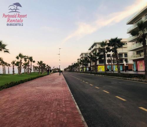 an empty street with palm trees and buildings at شاليه للايجار اليومى بورتو سعيد in Port Said