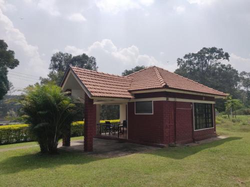 a small red brick house with a porch at Dubare Inn Coorg in Madikeri