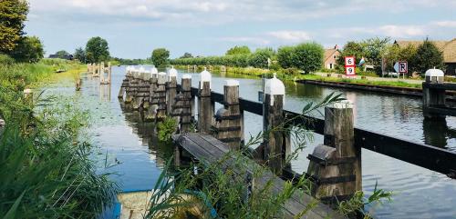 a river with a wooden fence in the water at Bed & Breakfast [H]eerlijk! in De Kwakel