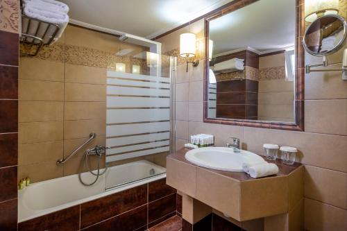 Un baño con lavabo, bañera y espejo. en Peridis Family Resort, en Cos