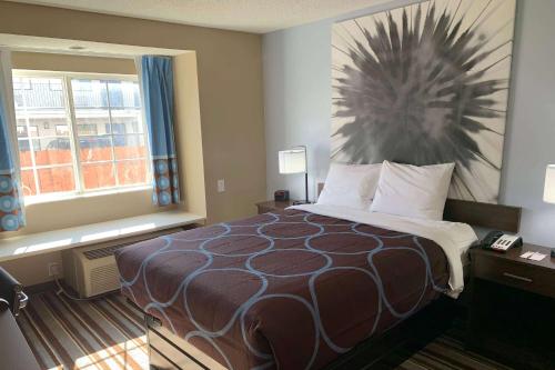 a hotel room with a bed and a window at Super 8 by Wyndham Joliet in Joliet