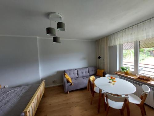 a bedroom with a bed and a table and a couch at Dom przy lesie in Zawadka