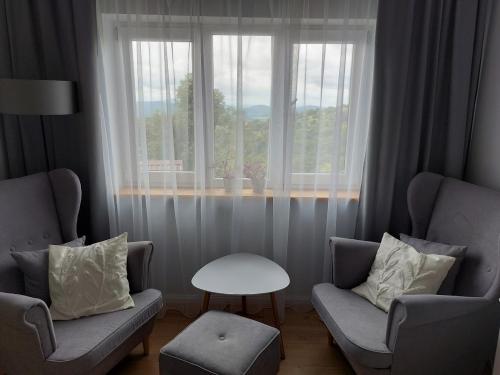 a living room with two chairs and a table and a window at Dom przy lesie in Zawadka