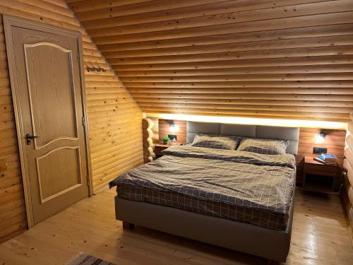 a bedroom with a bed with a wooden wall at Cottage Forest House in Skhidnitsa