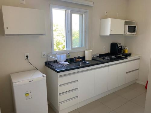 a white kitchen with a sink and a window at Apartamento em Holambra in Holambra