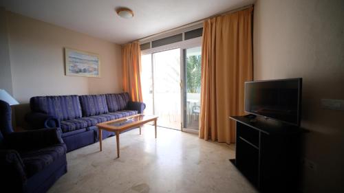 uma sala de estar com um sofá azul e uma televisão em Apartamentos Coronado em Marbella