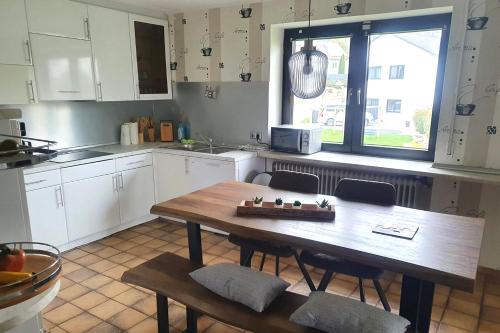 een keuken met witte kasten en een houten tafel en stoelen bij Work & stay apartment with balcony near Ingolstadt in Großmehring