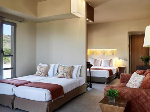 a hotel room with two beds and a couch at Aegeon Beach Hotel in Sounio
