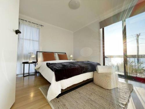 a bedroom with a large bed and a large window at The Shoreline - Absolute Beachfront 2BR Batehaven in Batehaven