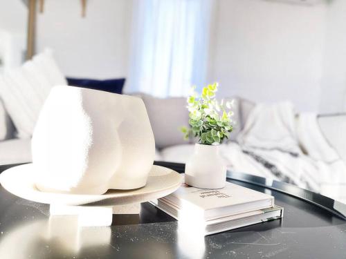 a table with a plate and a vase with flowers at The Shoreline - Absolute Beachfront 2BR Batehaven in Batehaven