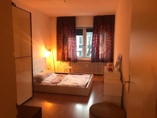 een kleine slaapkamer met een bed en een raam bij Cozy and central apartment in Düsseldorf