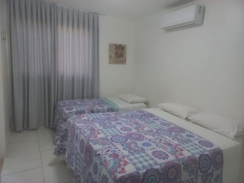 een slaapkamer met 2 bedden en een quilt. bij Reserva Imbassaí Vila dos Lirios in Imbassai