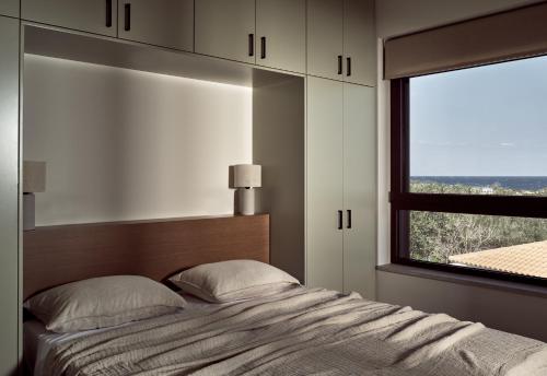 a bedroom with a bed with a large window at Zayn Luxury Villas, a Serene Escape, By ThinkVilla in Zakynthos Town