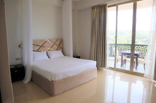 Schlafzimmer mit einem Bett und Blick auf einen Balkon in der Unterkunft The Voice Hotel in Entebbe