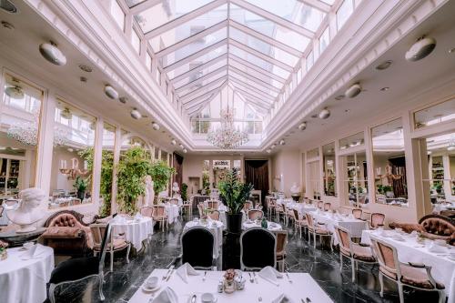 a dining room with white tables and chairs and a glass ceiling at Grand Palace Hotel - The Leading Hotels of the World in Riga