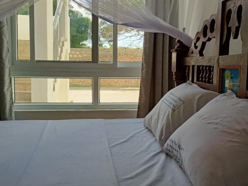 Schlafzimmer mit einem weißen Bett und einem Fenster in der Unterkunft PahaliMzuri Kijani - 1 Bedroom Beach Apartment with Swimming Pool in Malindi