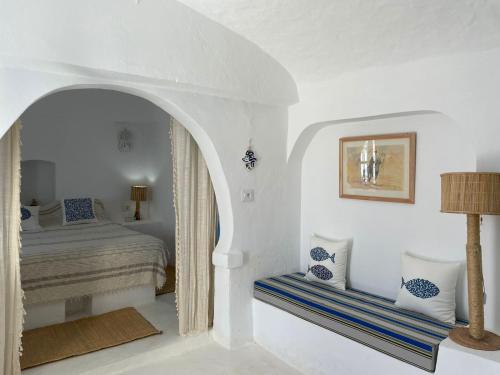 a white bedroom with a bed and a table at Dar Elbidha in Djerba