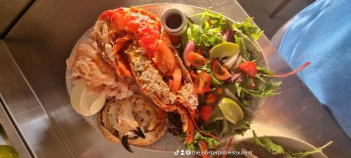 a plate of food with a sandwich and a salad at The Lobster Pot Cottage Church Bay in Llanrhyddlad