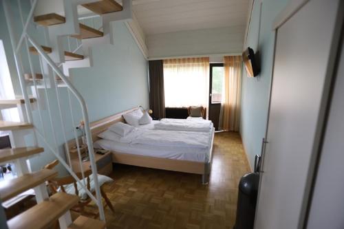 a small bedroom with a bed and a staircase at Gasthof - Pension Krämerhof in Thanstein