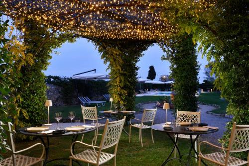 a patio with tables and chairs under an arch with lights at Villa Sabolini in Colle Val D'Elsa