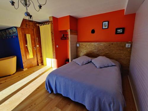 a bedroom with orange walls and a bed with two pillows at Chalet Ailleurs Appartement à Molines en Queyras in Molines-en-Queyras