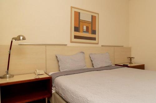 um quarto com uma cama com almofadas azuis e um candeeiro em Suíte na Savassi, fique perto de tudo! em Belo Horizonte