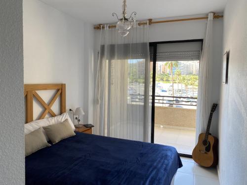 Un dormitorio con una cama azul y una guitarra en A28 - Frontmar - 2004 Finestrat s.l., en Cala de Finestrat