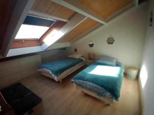 a attic bedroom with two beds and a window at DUPLEX les pieds dans l' eau in Jullouville-les-Pins