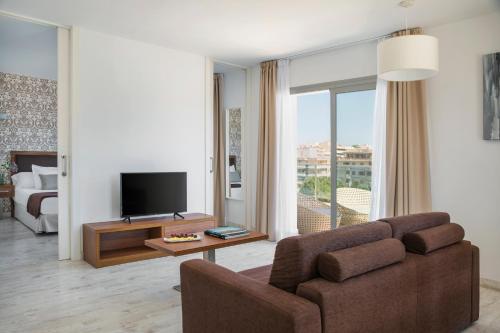 a living room with a couch and a television at Porto Drach Aparthotel & Suites in Porto Cristo