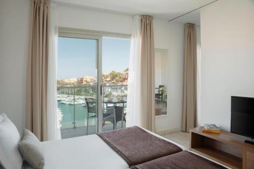 a hotel room with a bed and a view of a balcony at Porto Drach Aparthotel & Suites in Porto Cristo