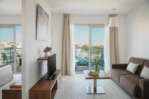a living room with a couch and a tv at Porto Drach Aparthotel & Suites in Porto Cristo