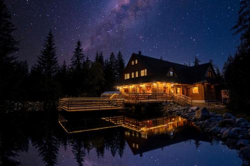 a house on a lake at night with the stars at Rezort pri jazere Podbanské in Pribylina