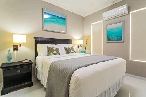 a bedroom with a large white bed with a night stand at Bida Marino Residence Aruba in Palm-Eagle Beach