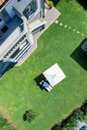 a person laying on a lawn with an umbrella at Verena's Boutique Villa au lac in Sachseln