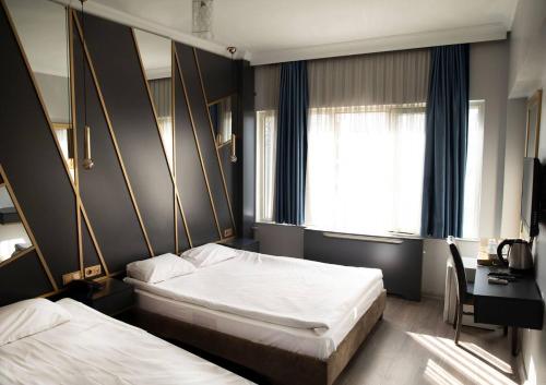 a bedroom with two beds and a desk and a window at Park Çağlayan Hotel in Istanbul