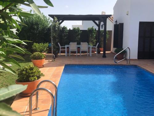 a swimming pool in a yard with a table and chairs at Stunning detached Villa in El Valle Golf Resort - ZO22EV in Murcia