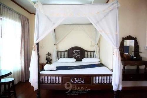 um quarto com uma cama de dossel num quarto em 9 เฮ้าส์ เชียงคาน em Chiang Khan