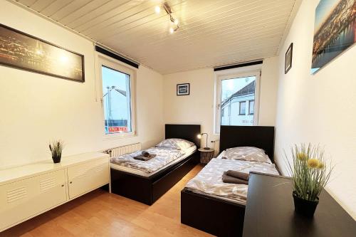 Duas camas num quarto com uma secretária e duas janelas em Centraly "work & stay Apartments" in Mechernich em Mechernich