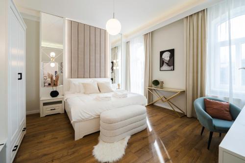 1 dormitorio con 1 cama blanca y 1 silla azul en ARTELIER - Trenčianske Teplice, en Trenčianske Teplice