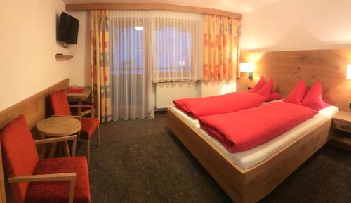 sypialnia z czerwonym łóżkiem, stołem i krzesłami w obiekcie Alpenrose Tux w mieście Tux