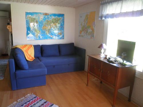 a living room with a blue couch and a desk at Lillstugan med annex in Stånga