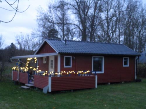 una pequeña casa roja con luces de Navidad en ella en Lillstugan med annex, en Stånga