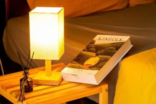 a table with a lamp and a book on a bed at D&D riverside Homestay in Xuân Sơn