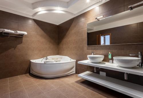 a bathroom with two sinks and a tub and a mirror at Casa Valcellina Hotel Ristorante in Montereale Valcellina