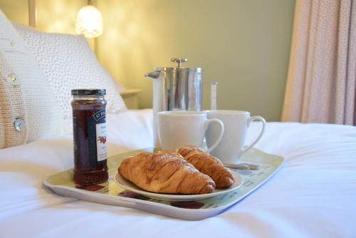 a tray with a plate of croissants and drinks on a bed at 11 Crabbe Street, Aldeburgh in Aldeburgh