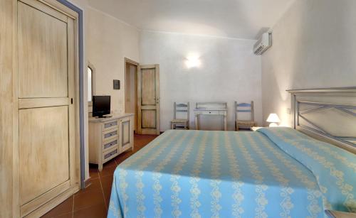 a bedroom with a blue bed and a television at Colonna Country Club in Porto Cervo